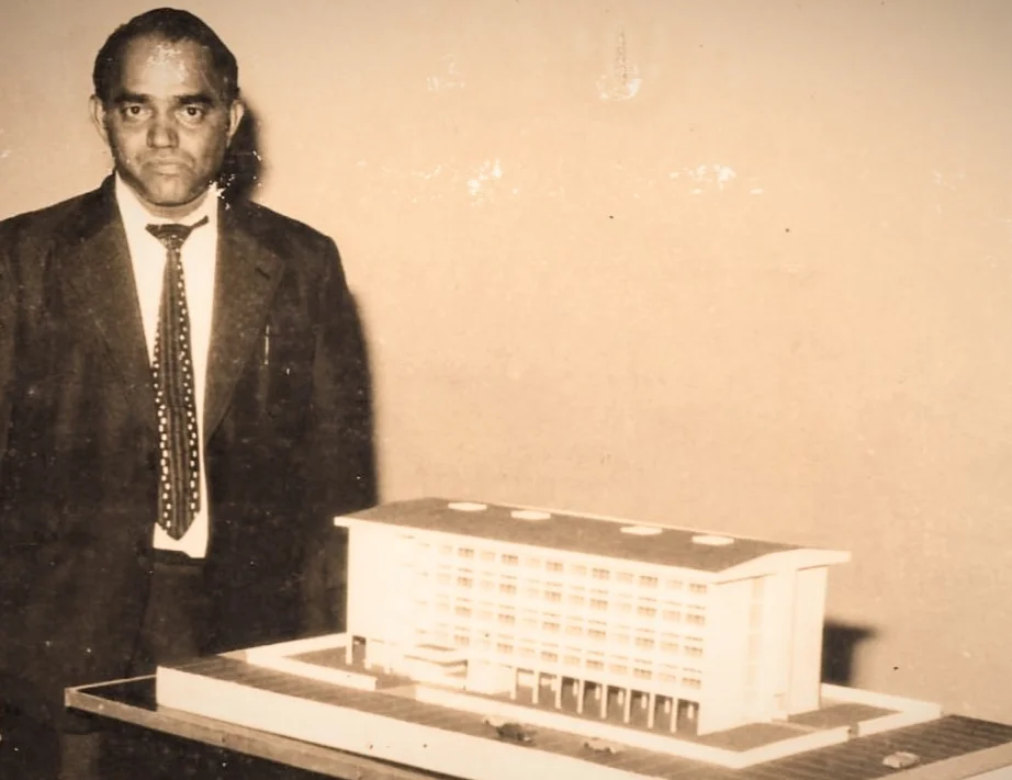 Lion K.B. Kotian standing beside an architectural model of the first draft of the school
